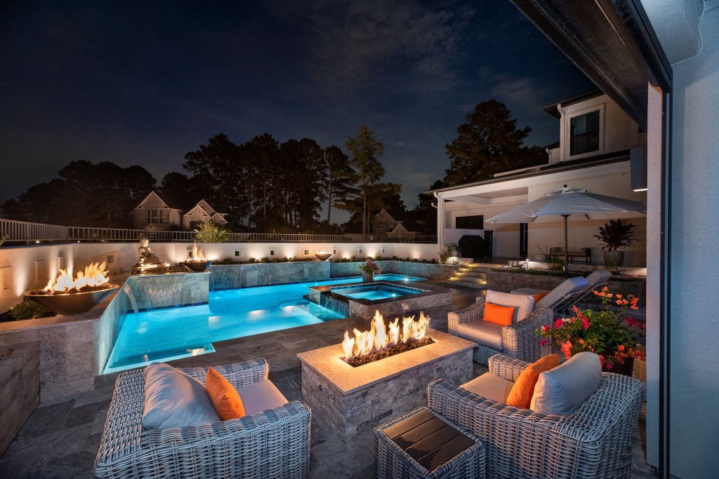 night view of outdoor fireplace with pool in background